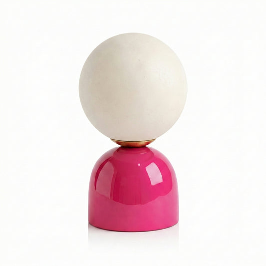 Table lamp with a pink base and white glass sphere on a white background