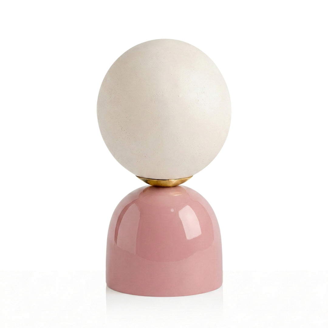 Decorative object with a white sphere on a pink base against a white background